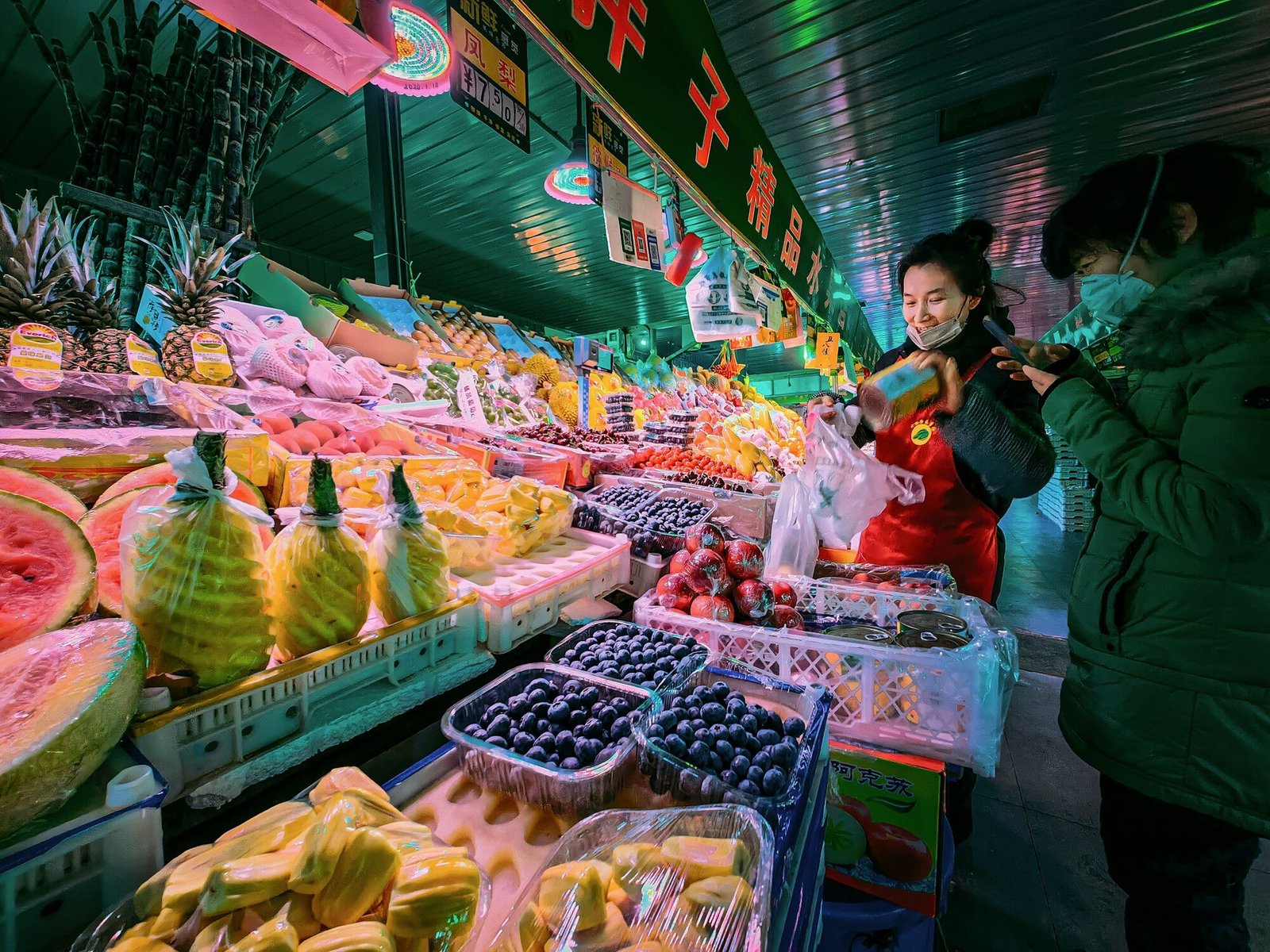a woman standing in front of a display of fruit