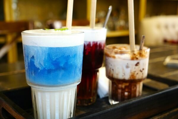Three colorful layered drinks with straws