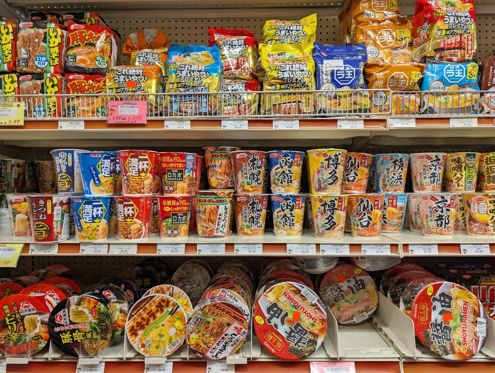 Shelves stocked with various instant noodle cups and packets.