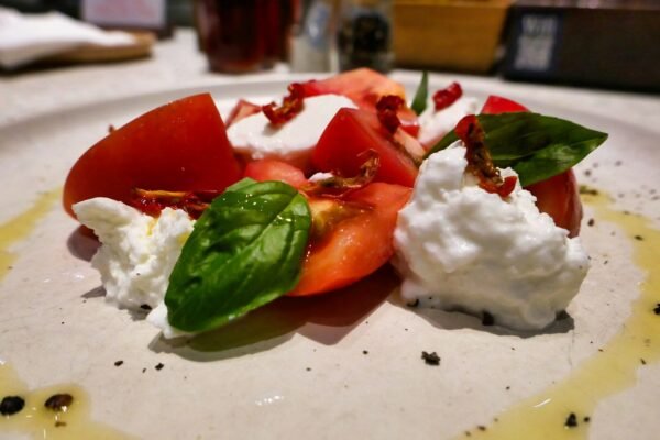 A white plate topped with sliced tomatoes and whipped cream