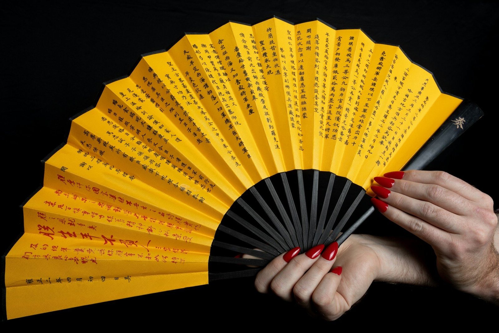 a woman holding a yellow and black fan
