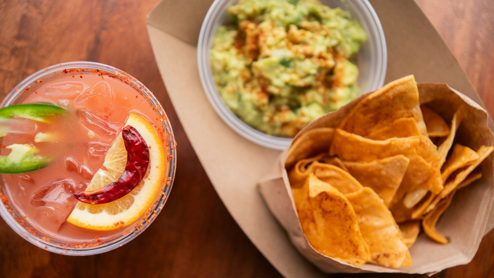 Refreshing drink, chips, and guacamole on a table.