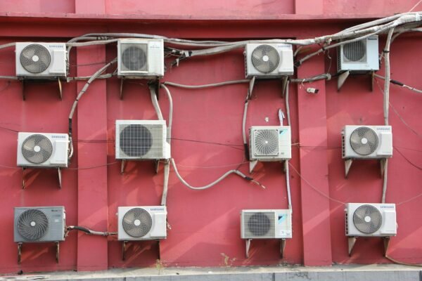 A bunch of air conditioners on a red wall