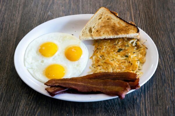 A white plate topped with eggs, bacon and toast